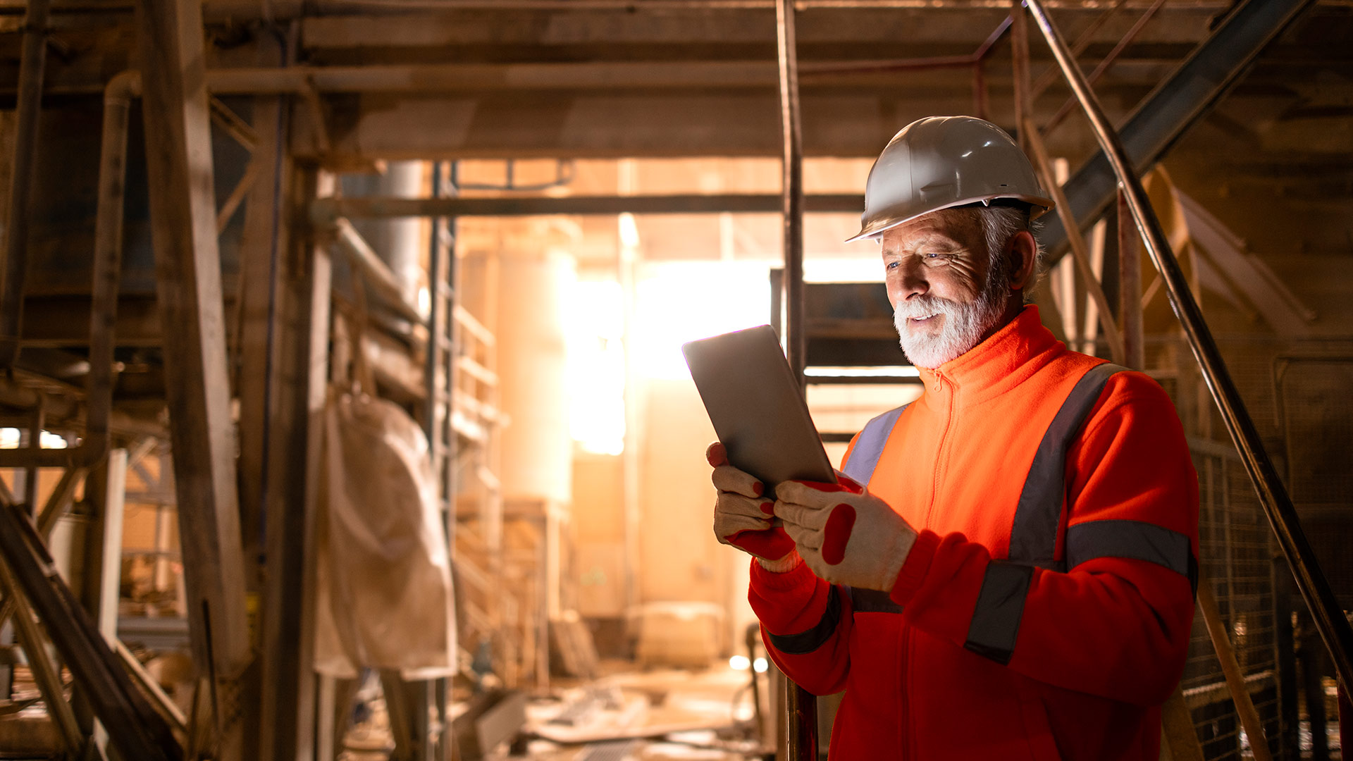 Ein Mitarbeiter betrachtet Inhalte auf einem Tablet in einer Produktionshalle